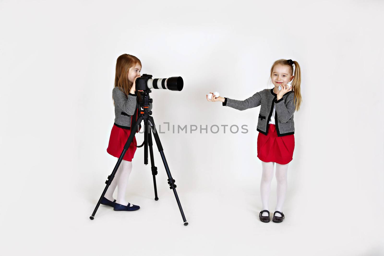Young girl using digital camera as a photographer with another girl