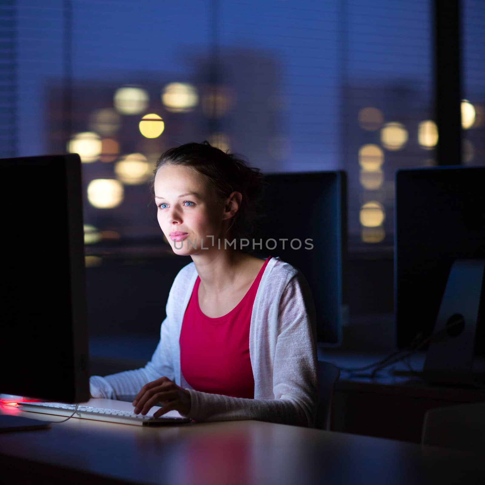 Pretty, young female college student using a desktop computer by viktor_cap