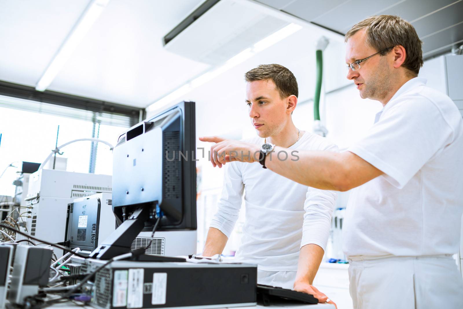 Team of researchers carrying out experiments in a lab (shallow DOF; color toned image)