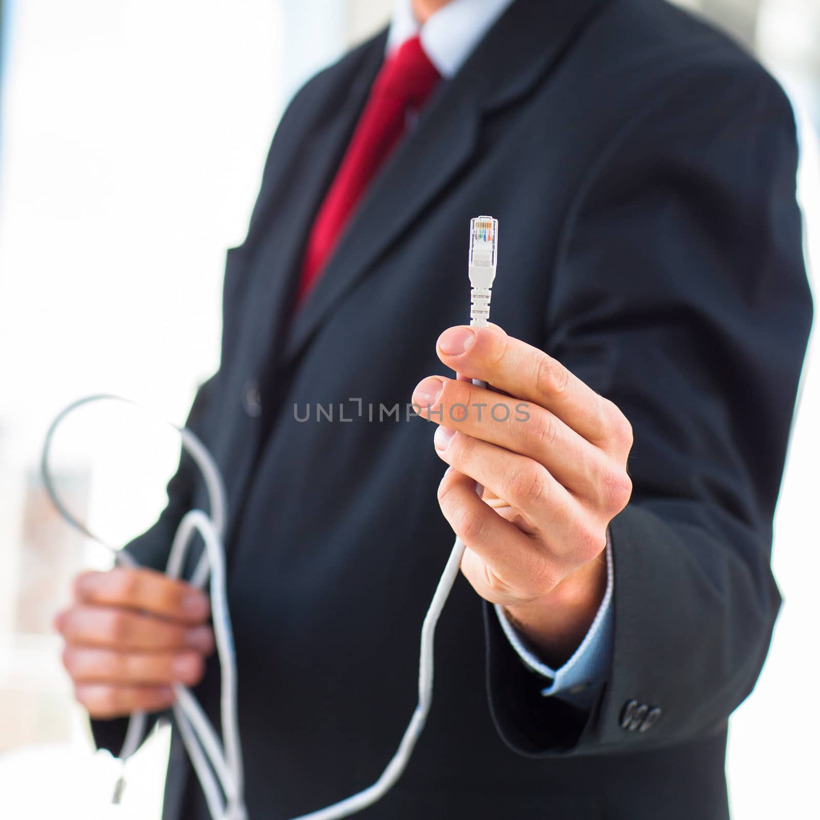 Young businessman holding an ethernet cable - stressing the importance of fast and reliable internet connection for a business (color toned image; shallow DOF)
