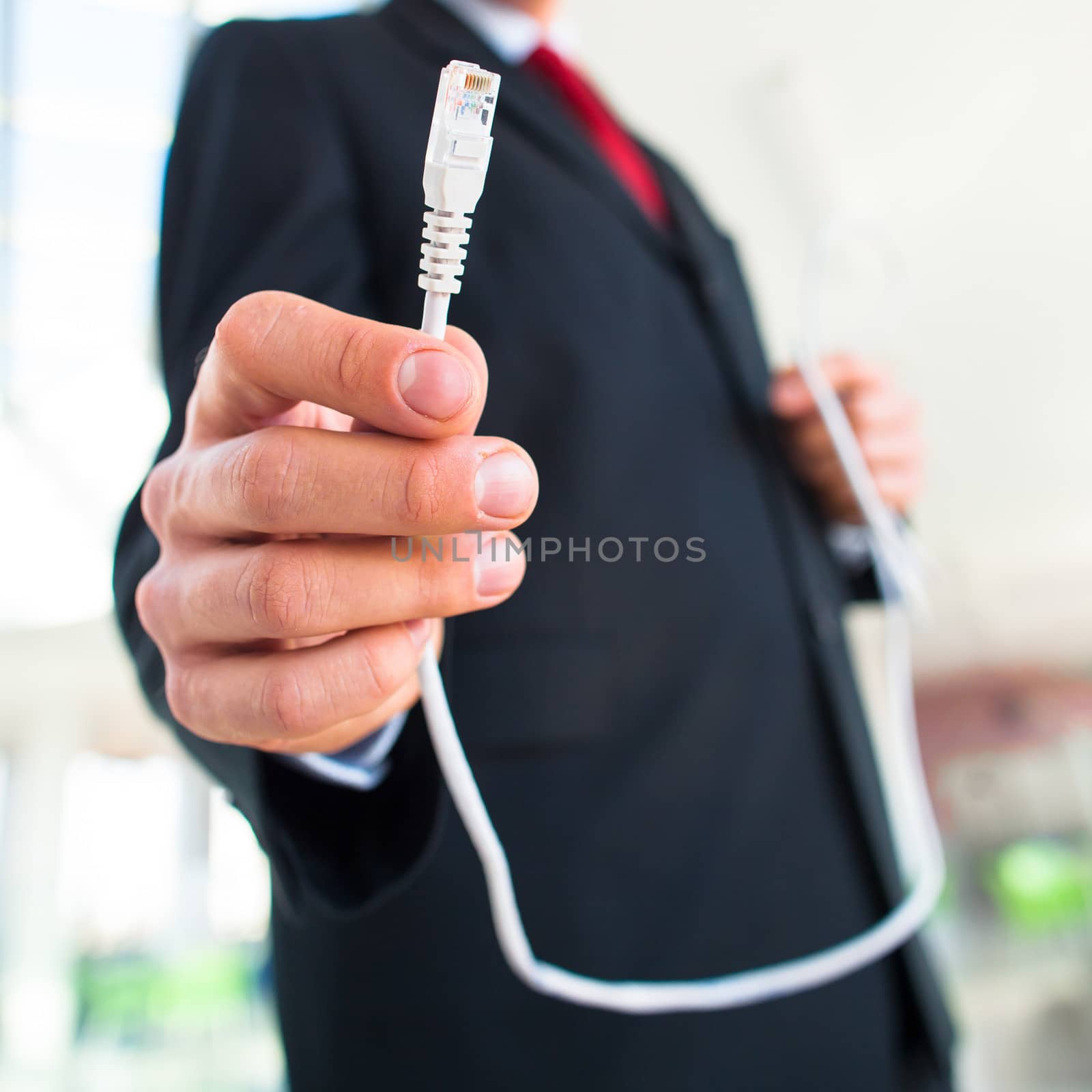 Young businessman holding an ethernet cable - stressing the impo by viktor_cap