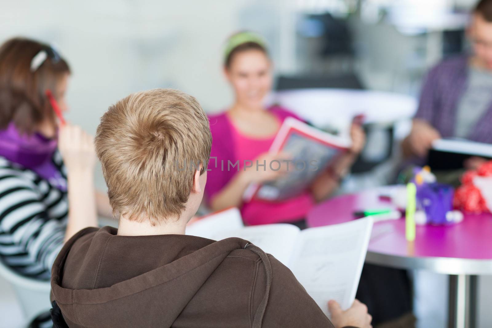 Group of college/university students during a brake between classes - chatting, comparing notes, having fun (shallow DOF; color toned image)