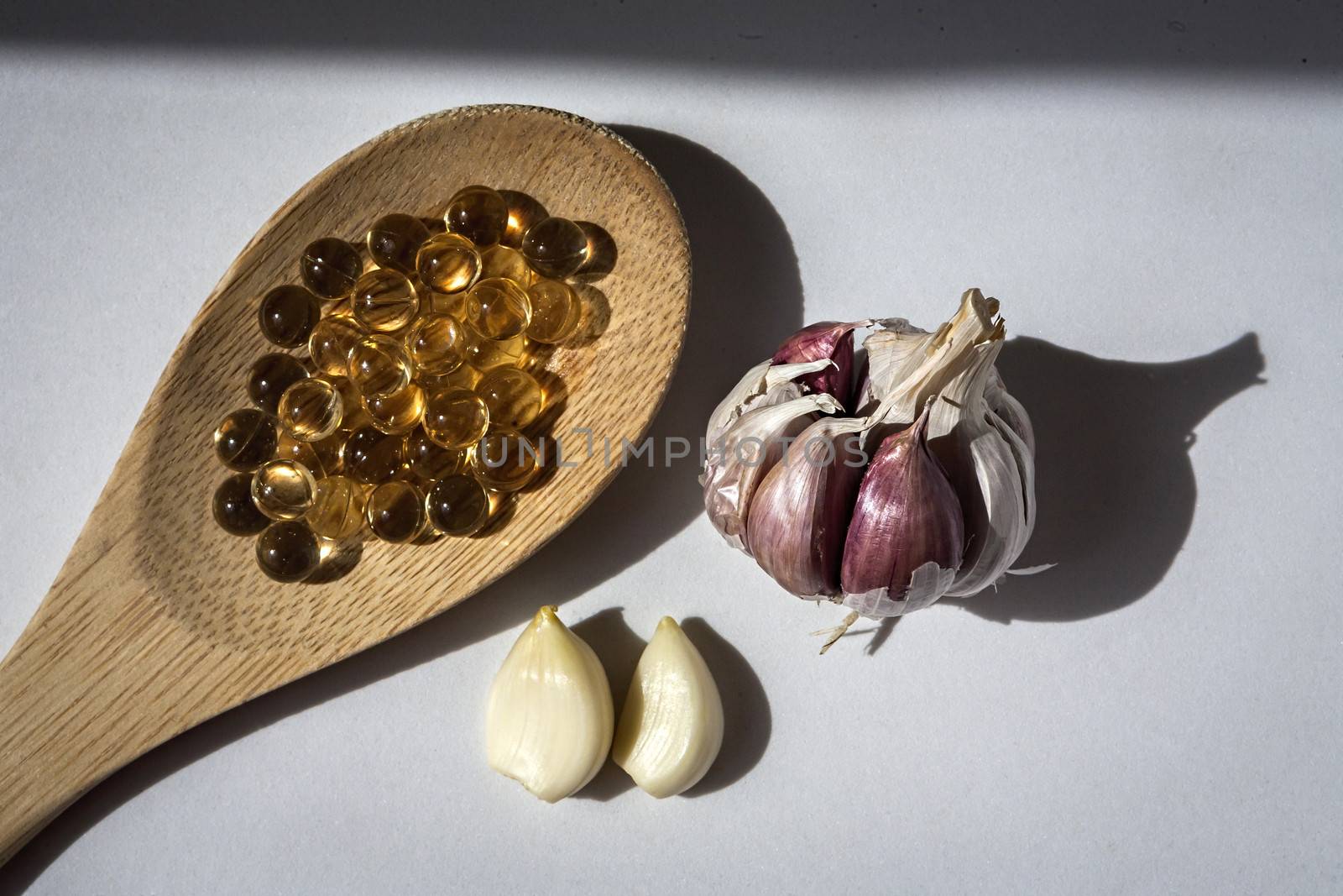 Pearls of garlic oil on wooden spoon, Garlic oil capsules, vitamins d pills 