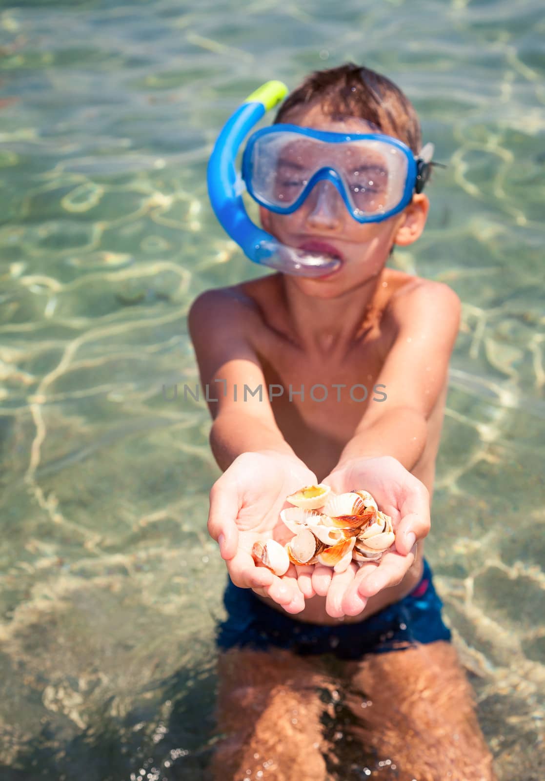 Boy wearing snorkeling gear showing seashells