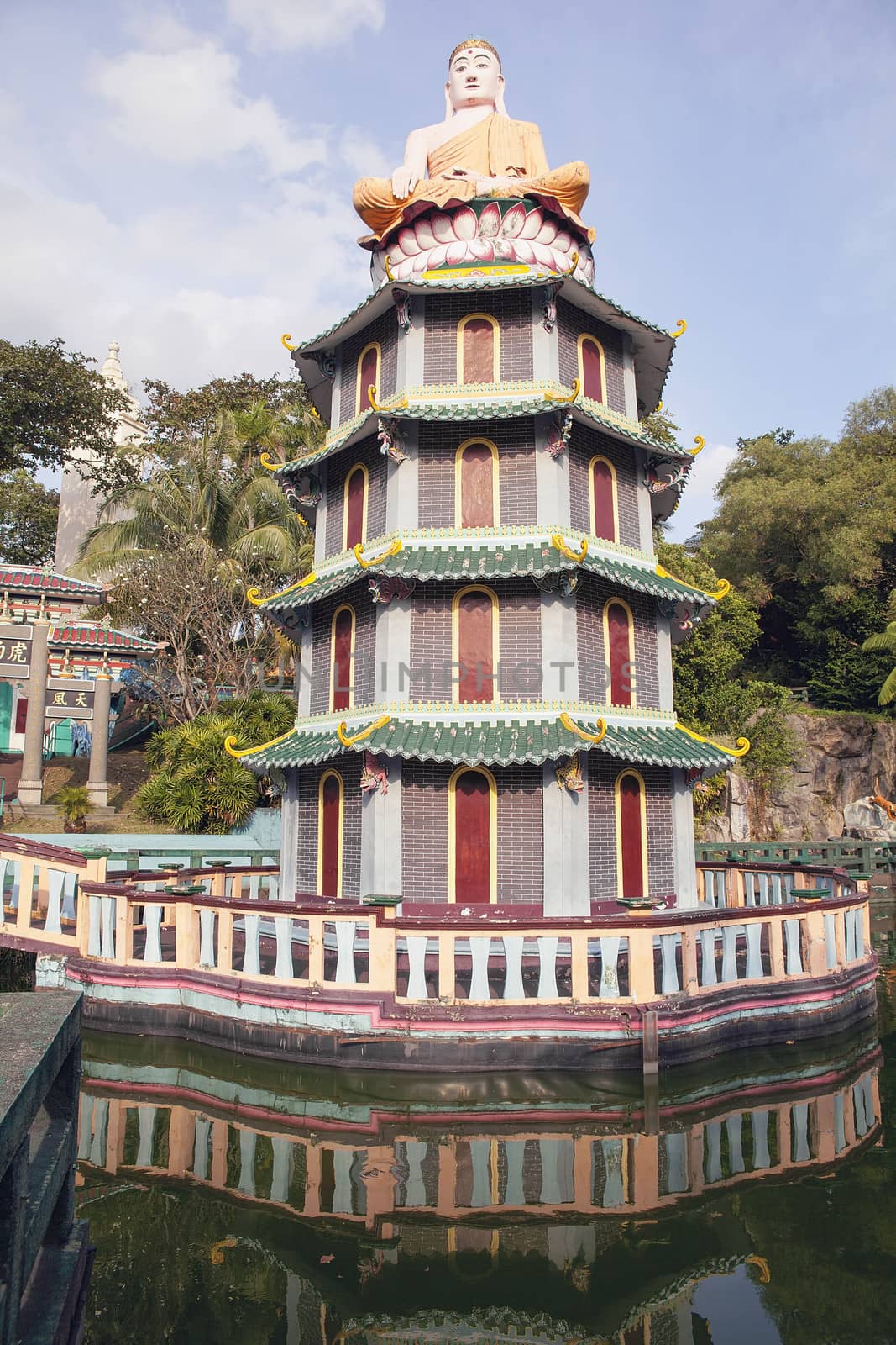 SINGAPORE - FEBRUARY 1, 2014: Buddha Statue Sitting on Top of Chinese Pagoda at Haw Par Villa Theme Park. This theme park contains over 1,000 statues and 150 giant dioramas depicting scenes from Chinese mythology, folklore, legends, and history.