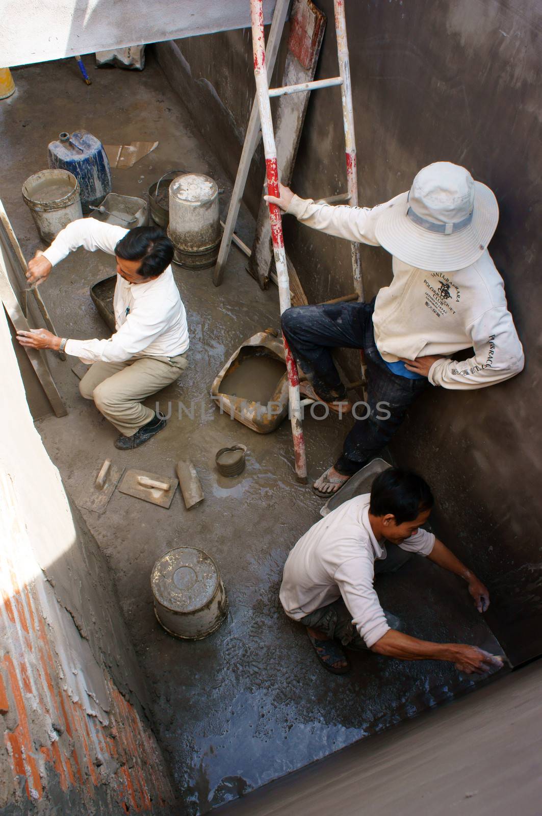 PHAN THIET, VIETNAM- JAN 21: Builder mortar at civil works, they working underground, with trowel in hand, mason cover mortar layer on brick wall to make solid, Viet Nam, Jan 21, 2014 