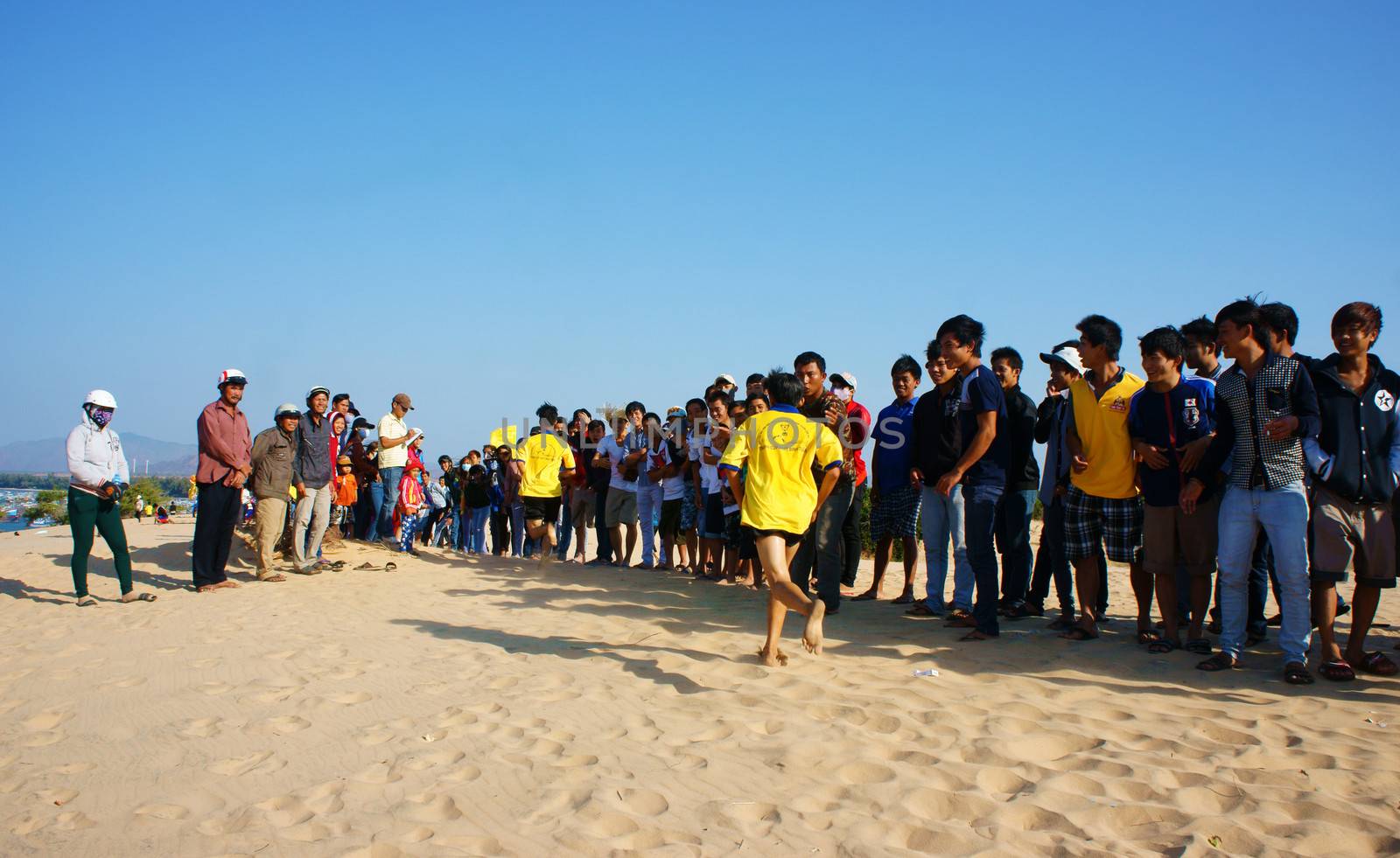 BINH THUAN, VIETNAM- FEB 14: Runner finish in marathon cross sand hill race, supporter standing in row to encourage, this's public sport activity to cheer healthy lifestyle, Viet Nam, Feb 14, 2014