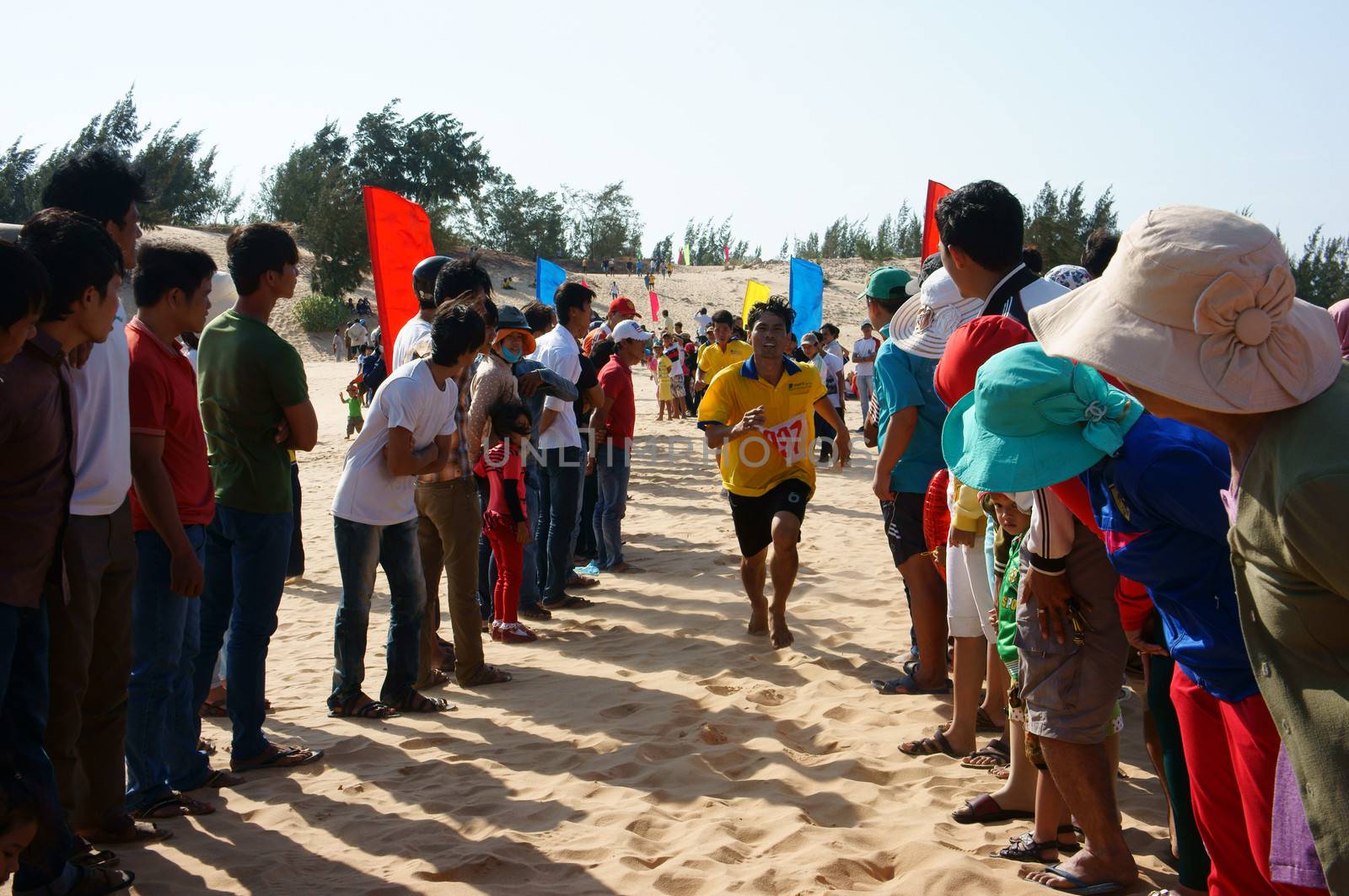 BINH THUAN, VIETNAM- FEB 14: Runner finish in marathon cross sand hill race, supporter standing in row to encourage, this's public sport activity to cheer healthy lifestyle, Viet Nam, Feb 14, 2014