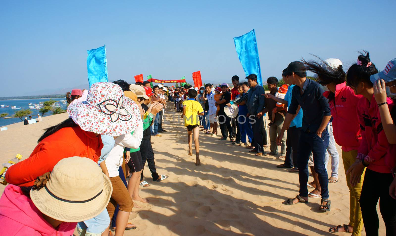 BINH THUAN, VIETNAM- FEB 14: Runner finish in marathon cross sand hill race, supporter standing in row to encourage, this's public sport activity to cheer healthy lifestyle, Viet Nam, Feb 14, 2014