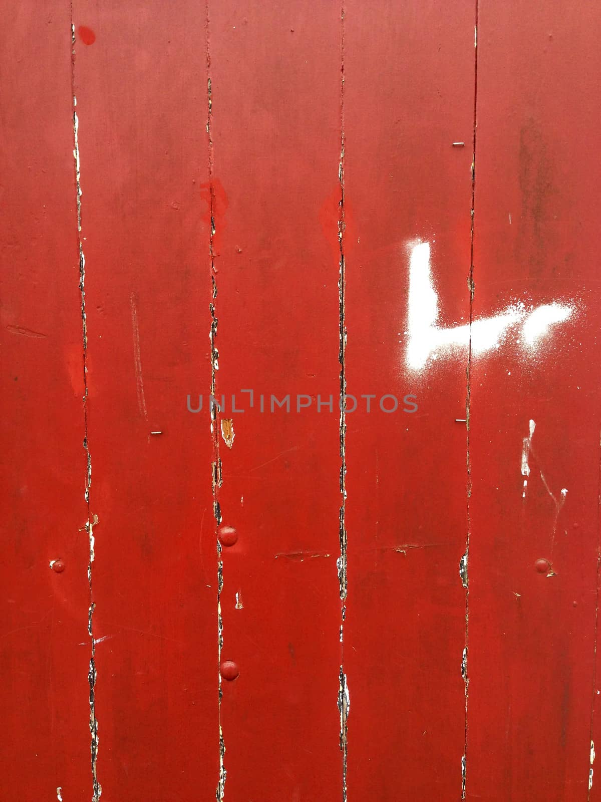 Closeup of red flaking paint on boards