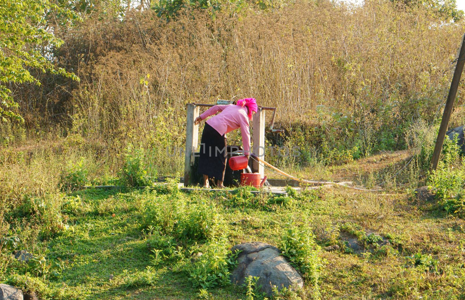  DAKLAK, VIETNAM- FEB 6: People  scoop water from water well by bucker, woman wear colorful clothing, the well at meadow in Vietnamese countryside, Viet Nam, Feb 6, 2014  