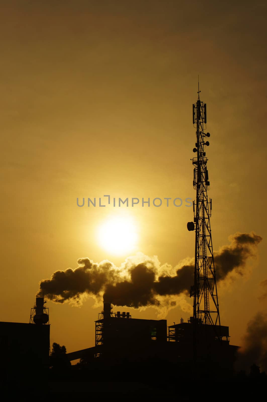 Black smoke from smoke stack of factory in industrial zone rose in to the air, it make polluted enviroment, the plant in silhouette at sunrise, atmosphere cover with waste exhaust