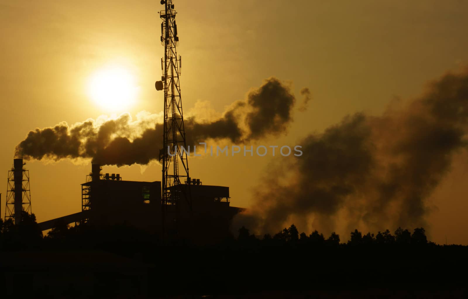 Black smoke from smoke stack of factory in industrial zone rose in to the air, it make polluted enviroment, the plant in silhouette at sunrise, atmosphere cover with waste exhaust