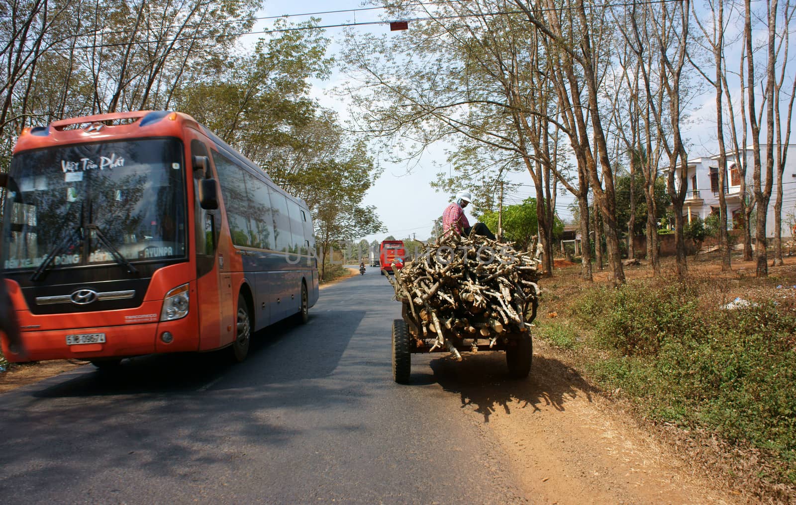 DAKLAK, VIETNAM- FEB 8 Traffic of transport vehicle on highway, the asphalt road pass jungle, passenger car and farm vehicle moving on day, Viet Nam, Feb 8, 2014