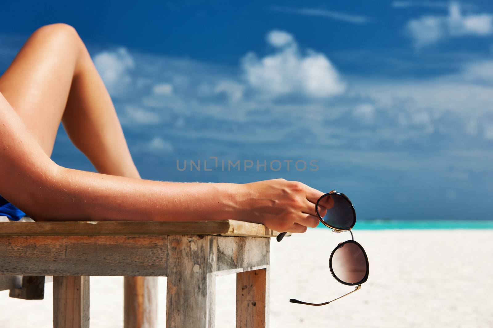 Woman at beach holding sunglasses by haveseen