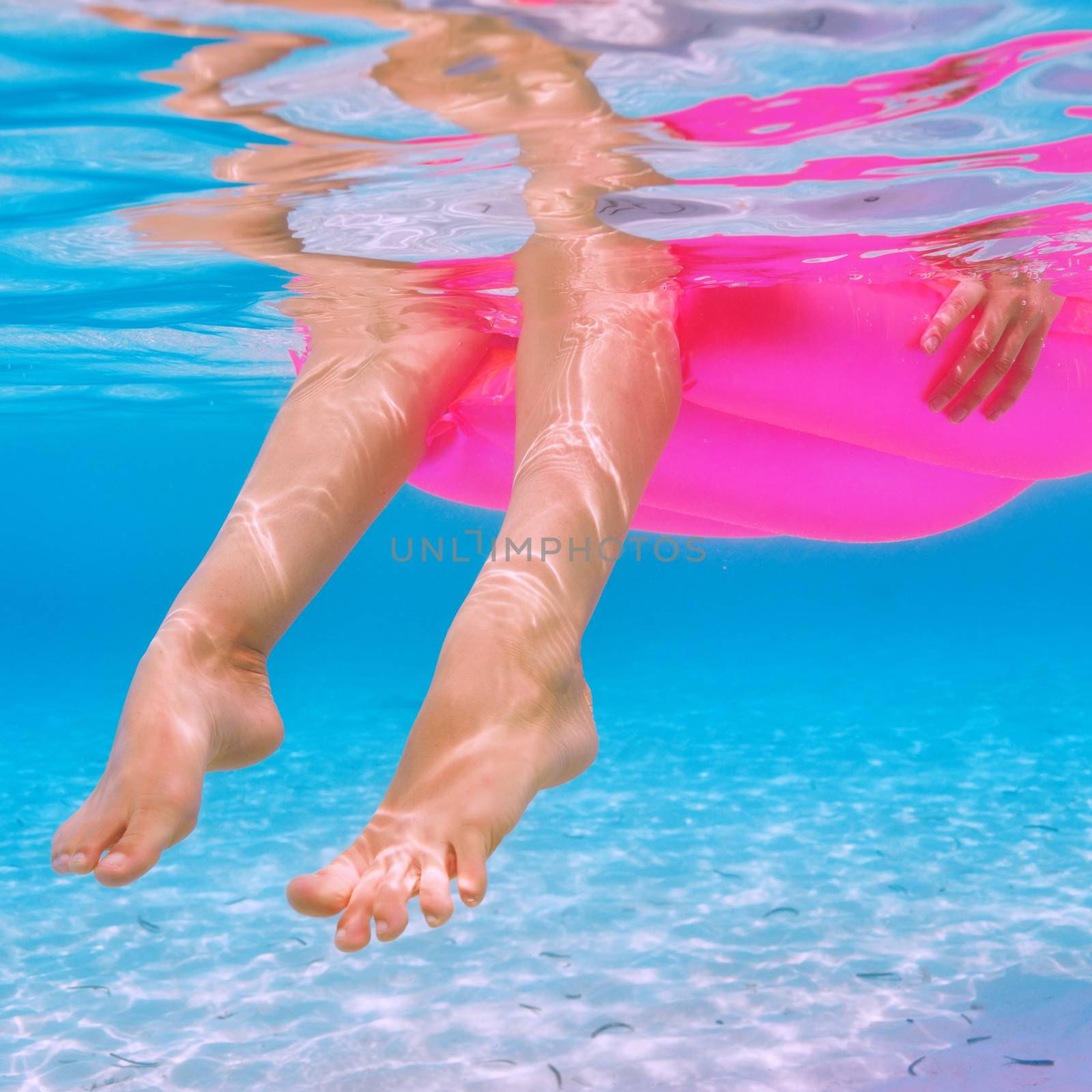 Woman relaxing on inflatable mattress at the beach, view from underwater