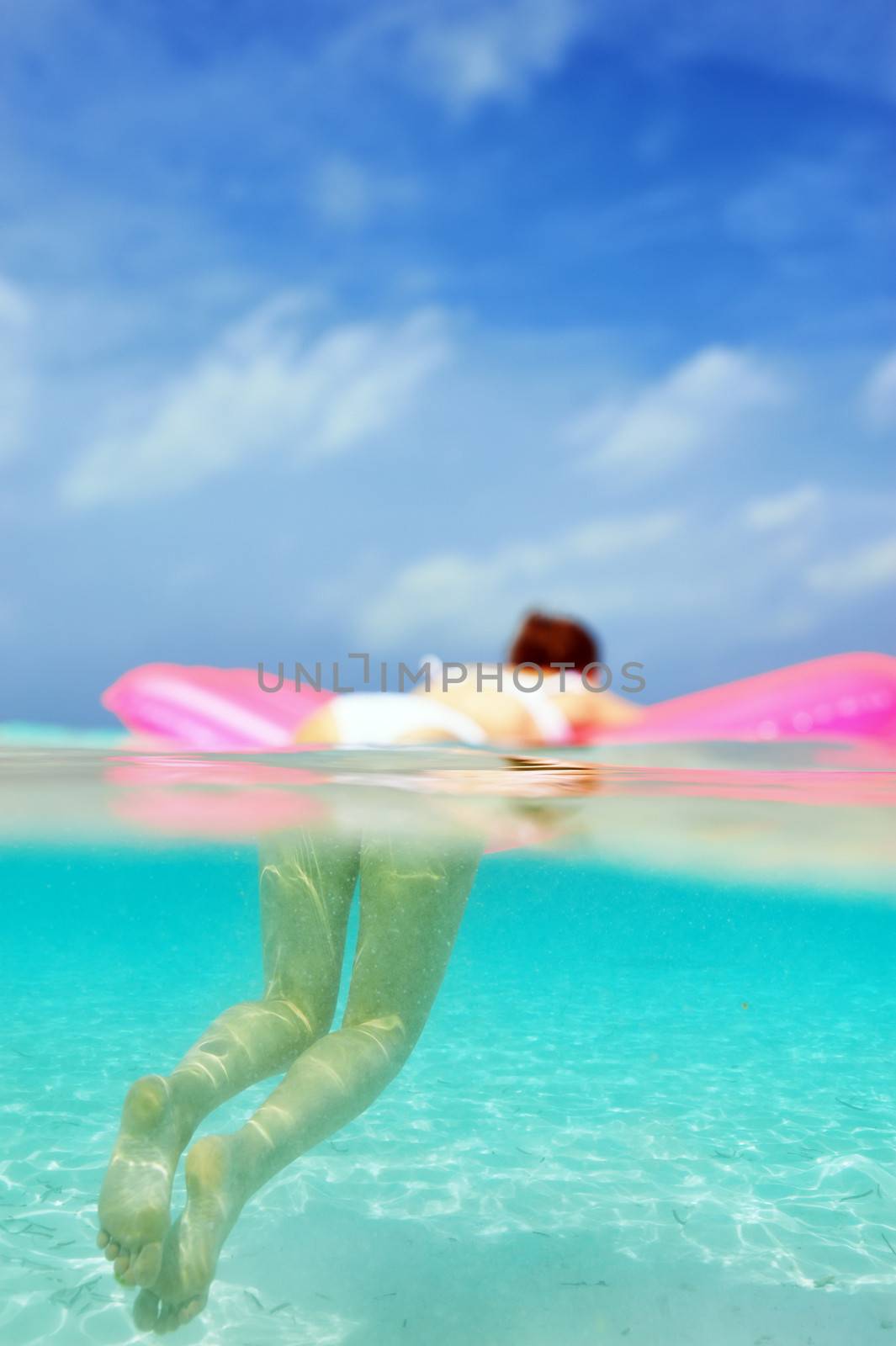 Woman relaxing on inflatable mattress at the beach, view from underwater