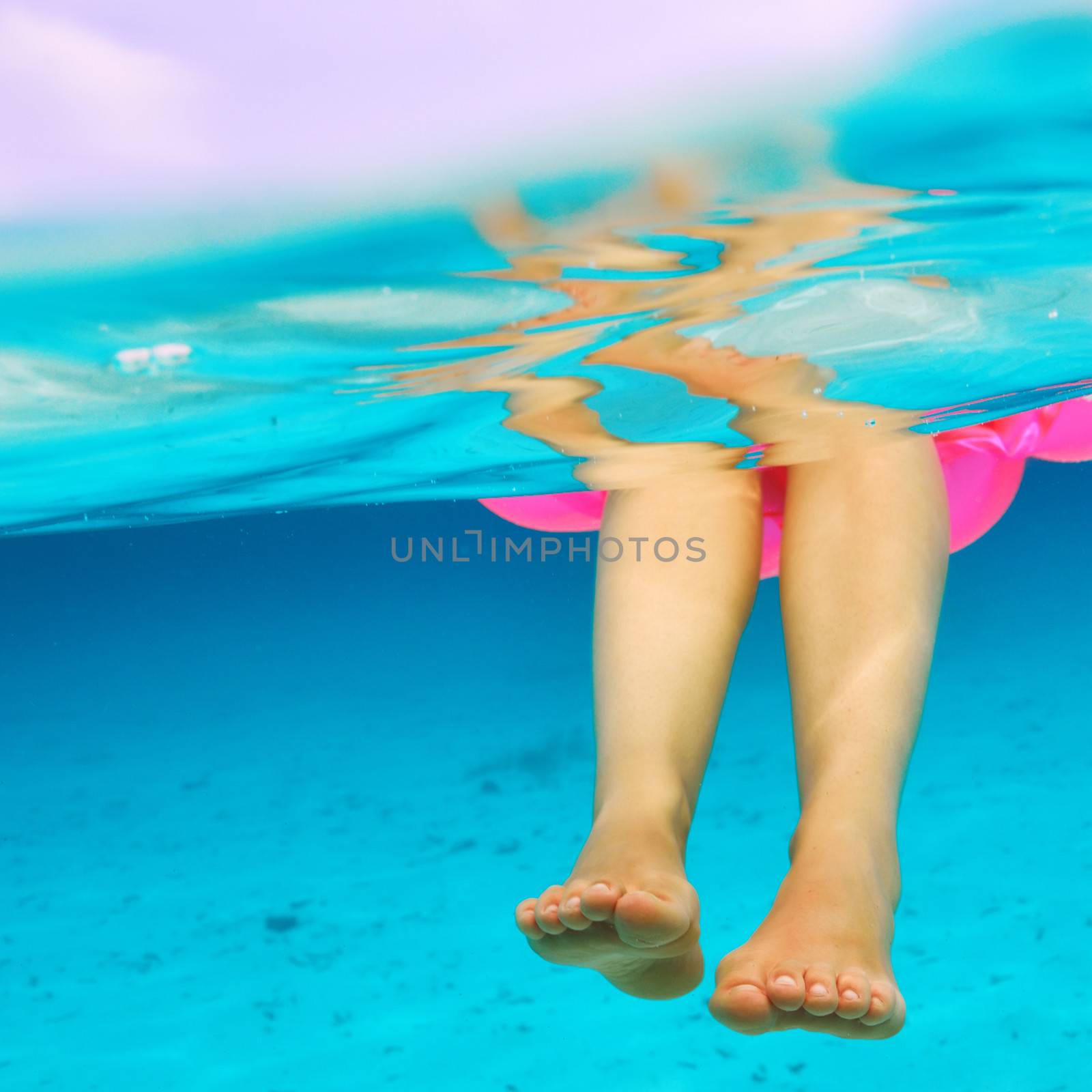 Woman relaxing on inflatable mattress at the beach, view from underwater