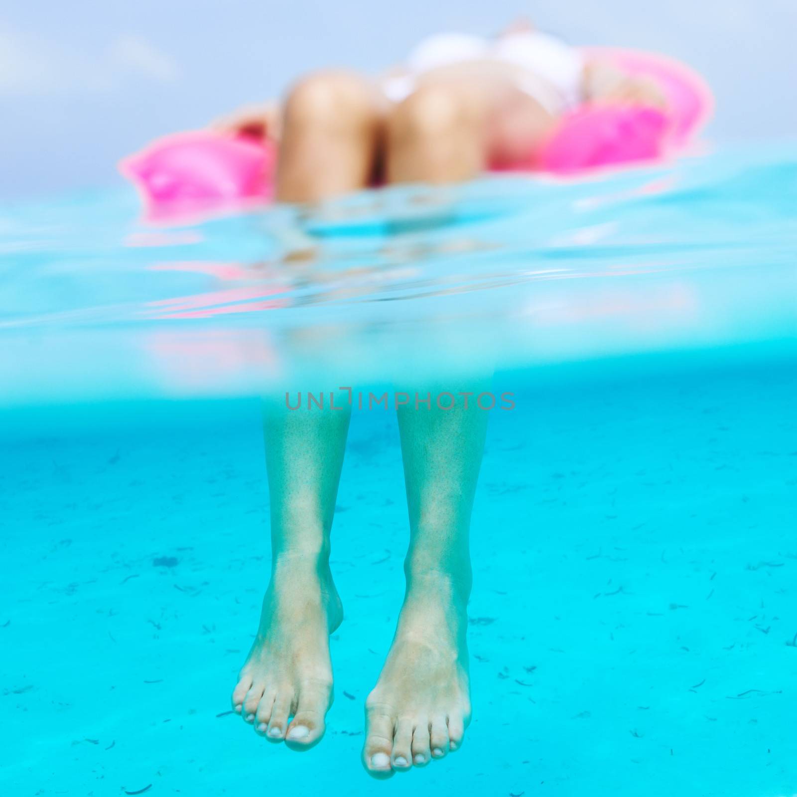 Woman relaxing on inflatable mattress, view from underwater by haveseen