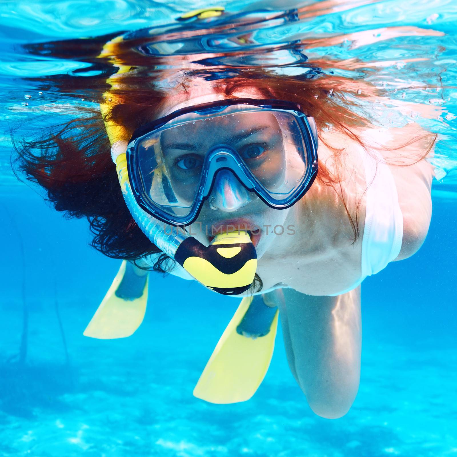 Woman with mask snorkeling in clear water 