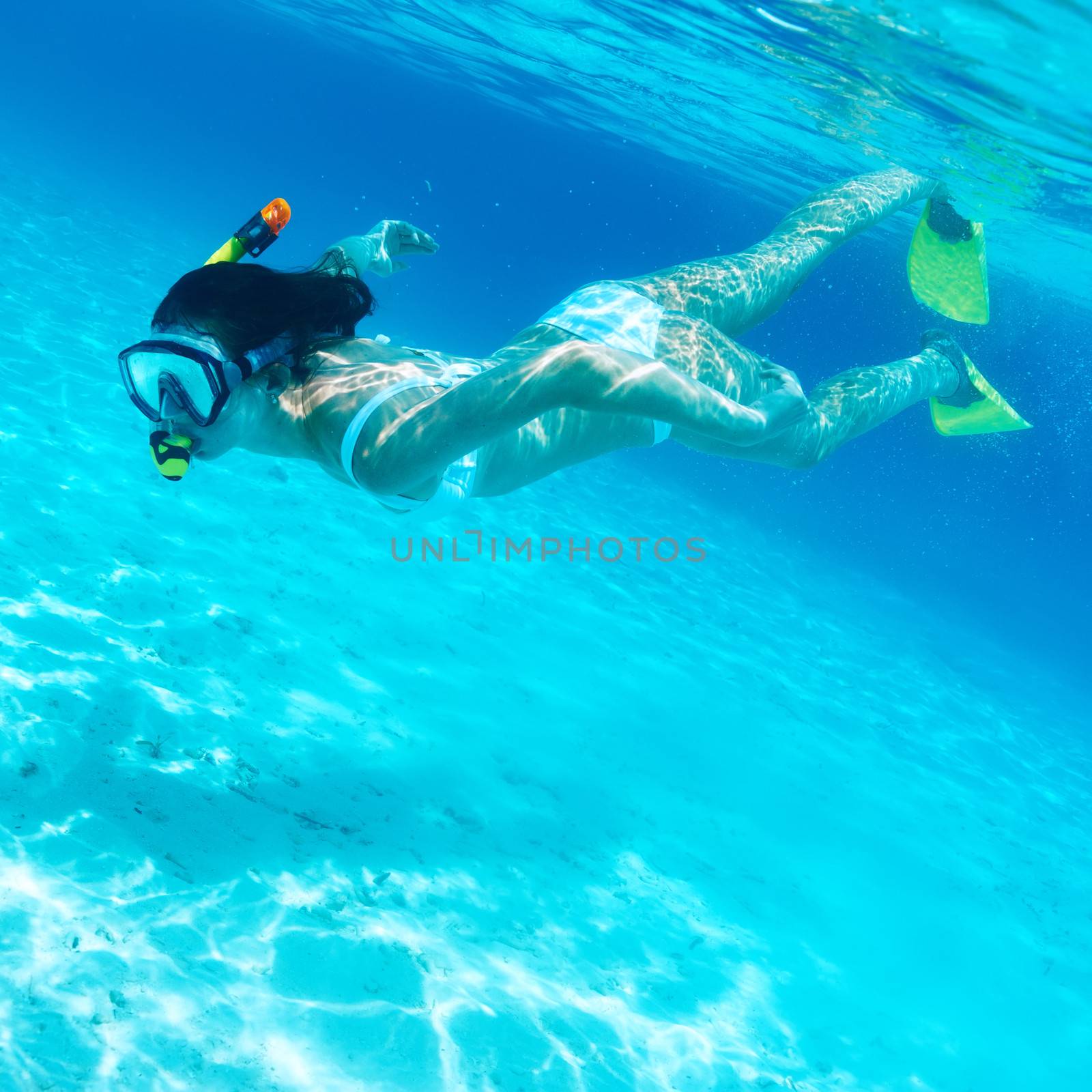 Woman with mask snorkeling in clear water 