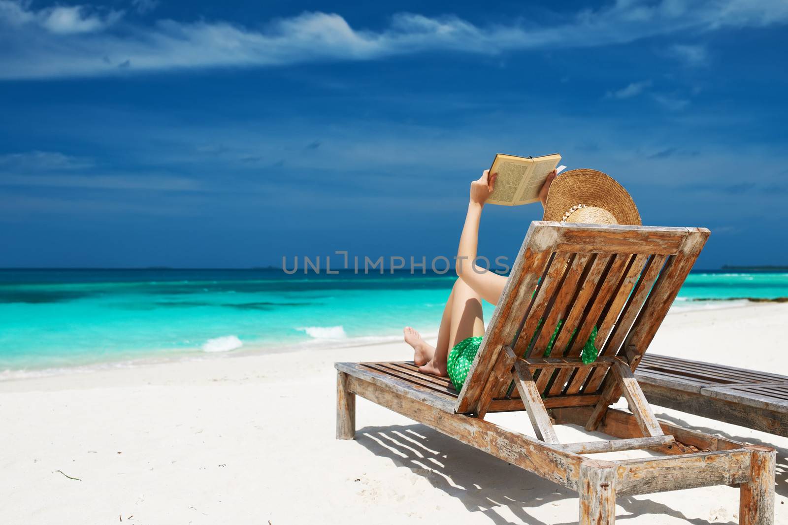 Young woman reading a book at beach by haveseen