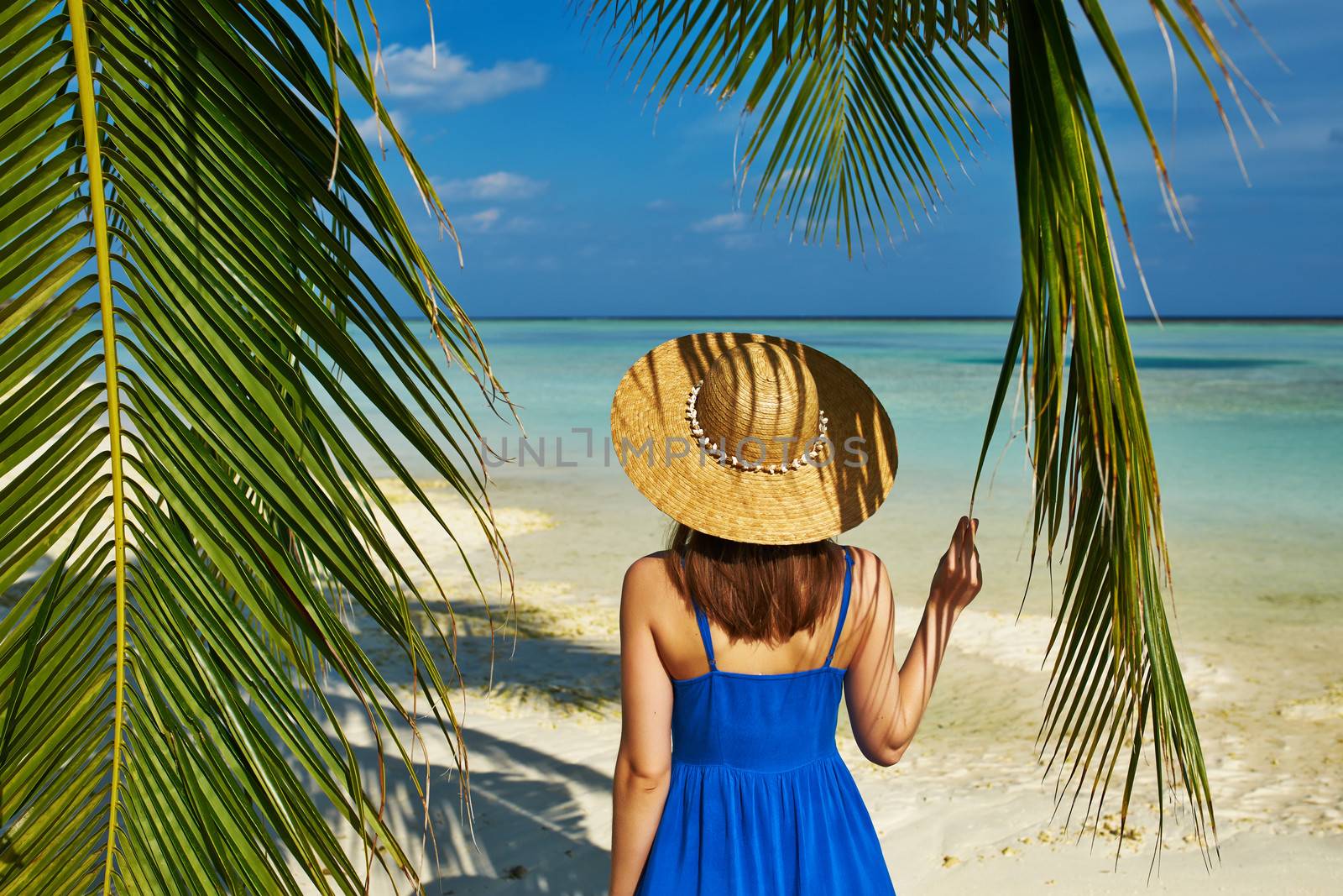 Woman in blue dress on a tropical beach at Maldives