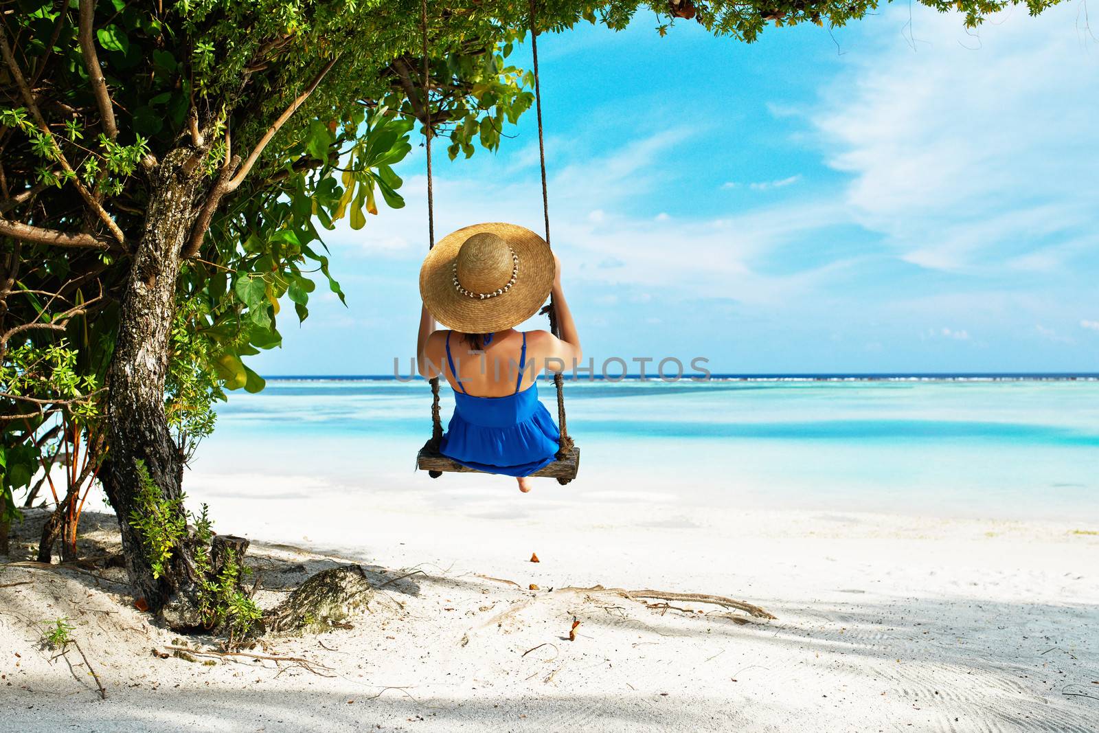 Woman in blue dress swinging at beach by haveseen