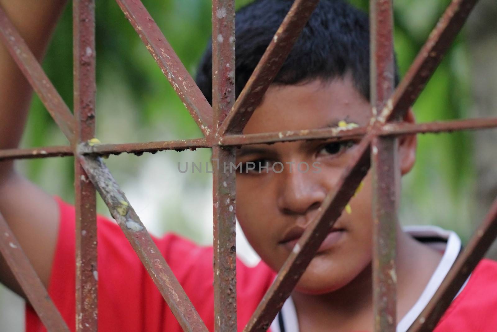 Portrait of Asian Thai boy behind an iron lattice 
