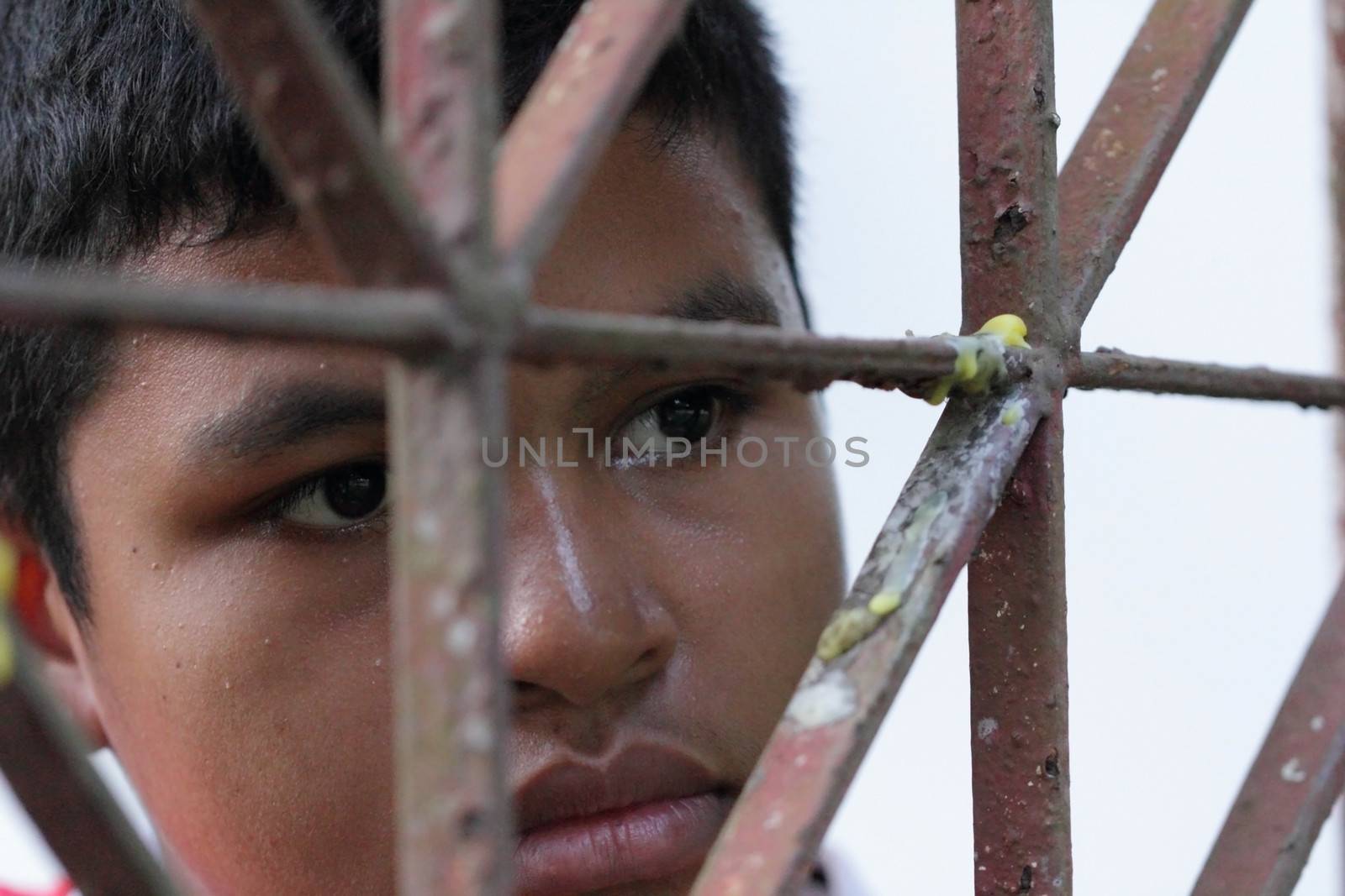 Portrait of Asian Thai boy behind an iron lattice 