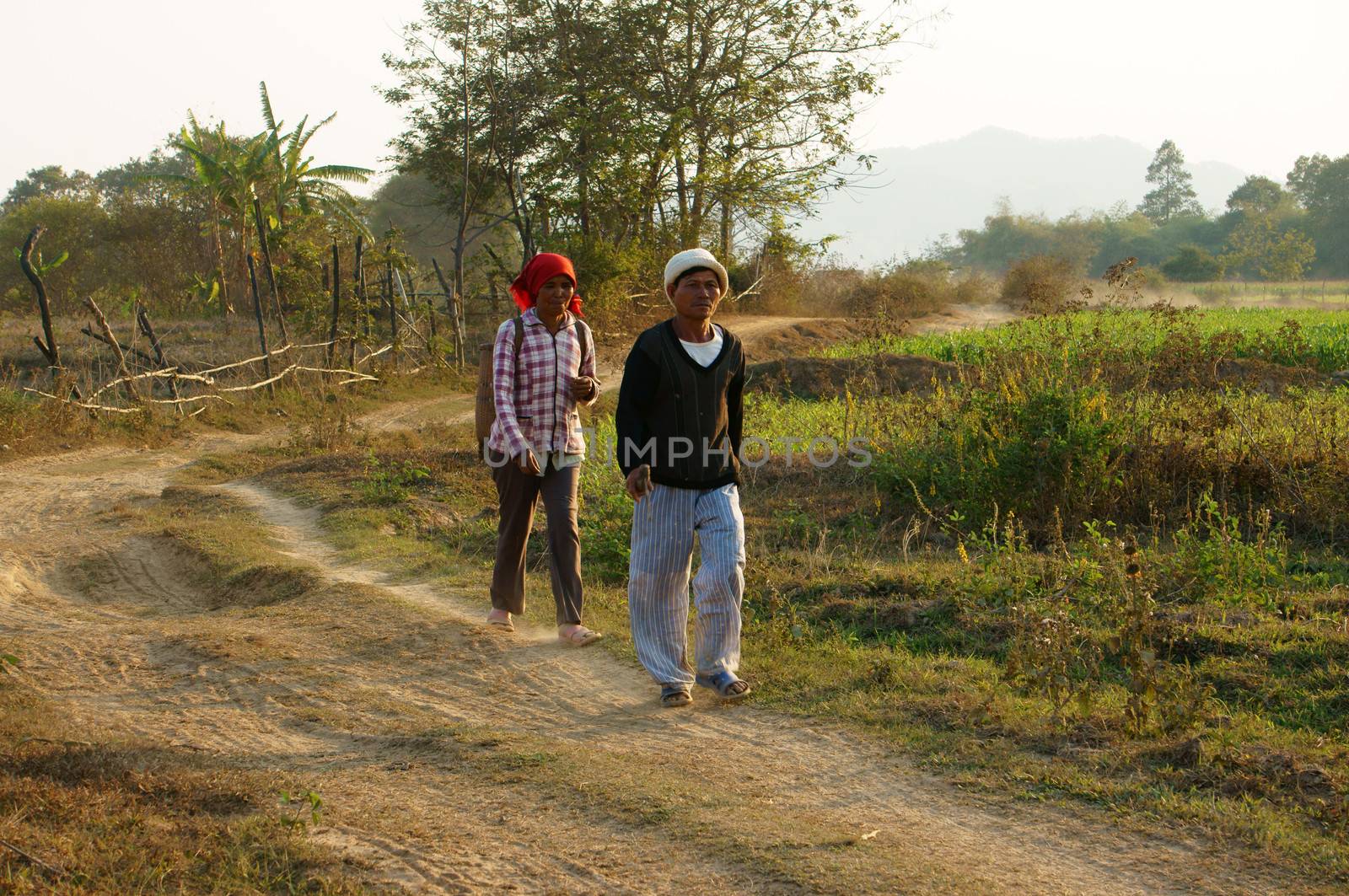 DAKLAK, VIETNAM- FEB 7: Couple of farmer walking on path at countryside to coming home, they walk on dust track in evening make calm view, Viet Nam, Feb 7, 2014