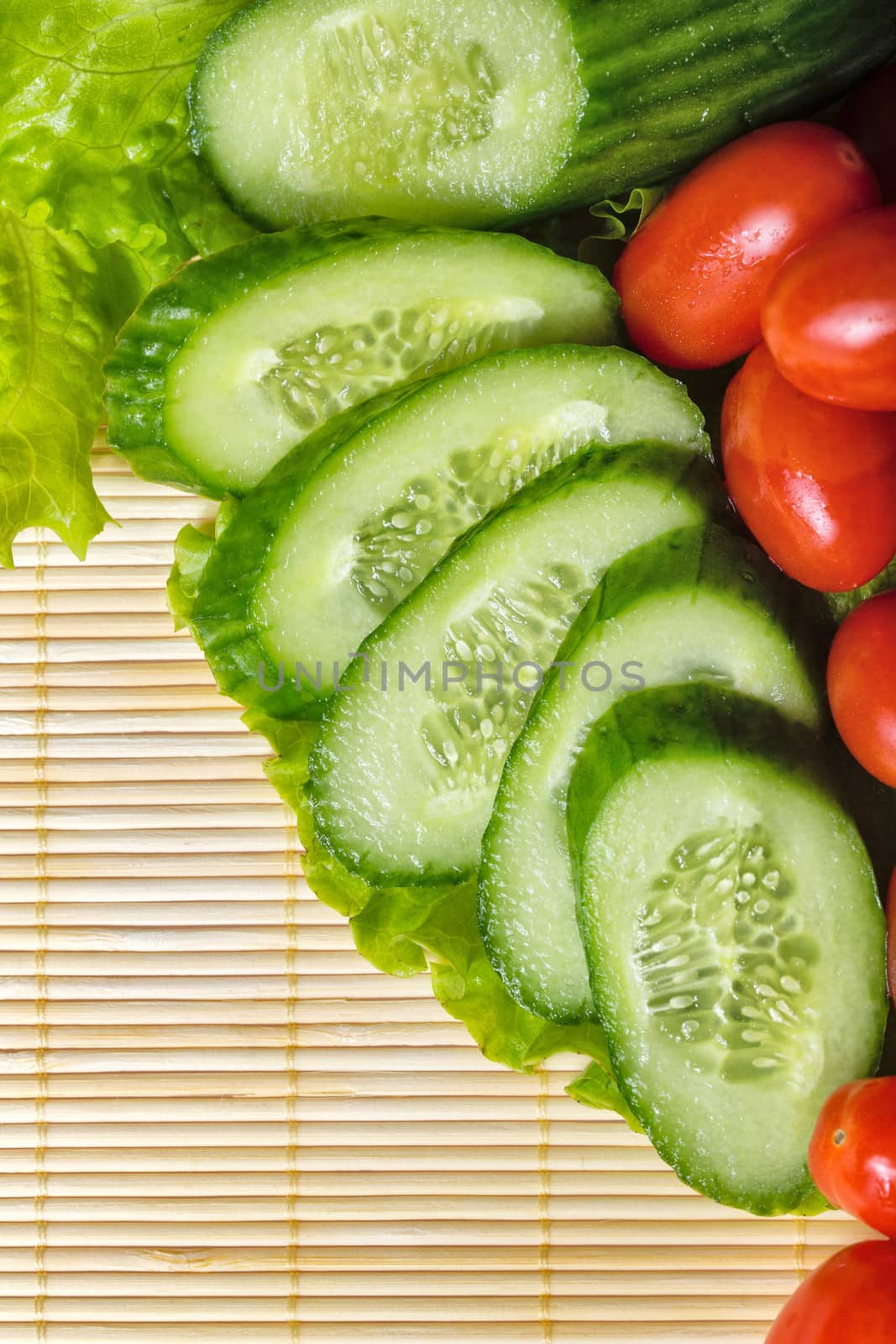 Ripe cherry tomatoes, cucumbers and lettuce closeup shot