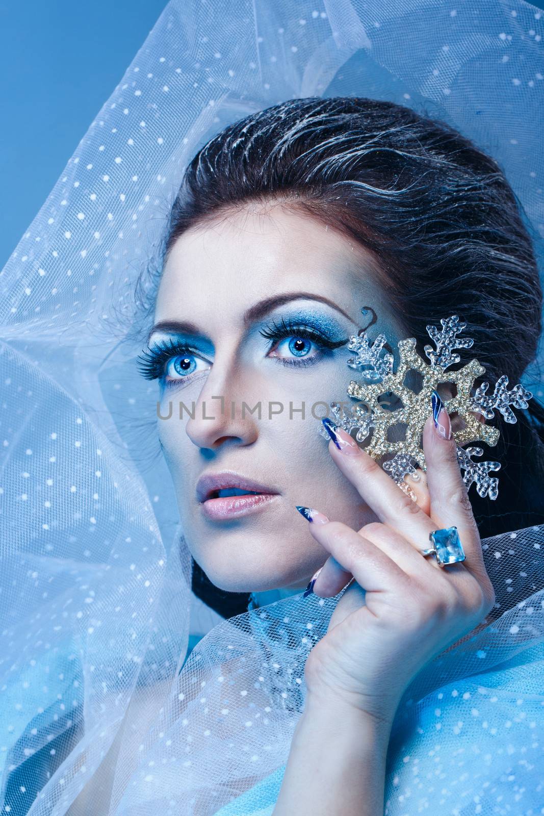 Girl with scenic make-up of the Snow Queen is holding a snowflake shot closeup