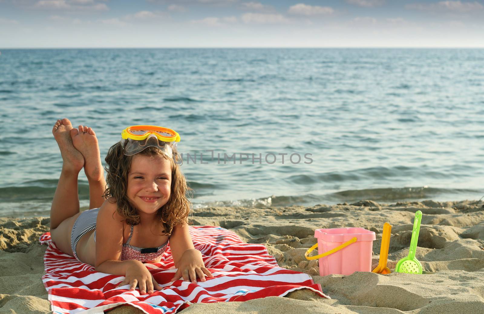 happy little girl lying on beach summer season by goce