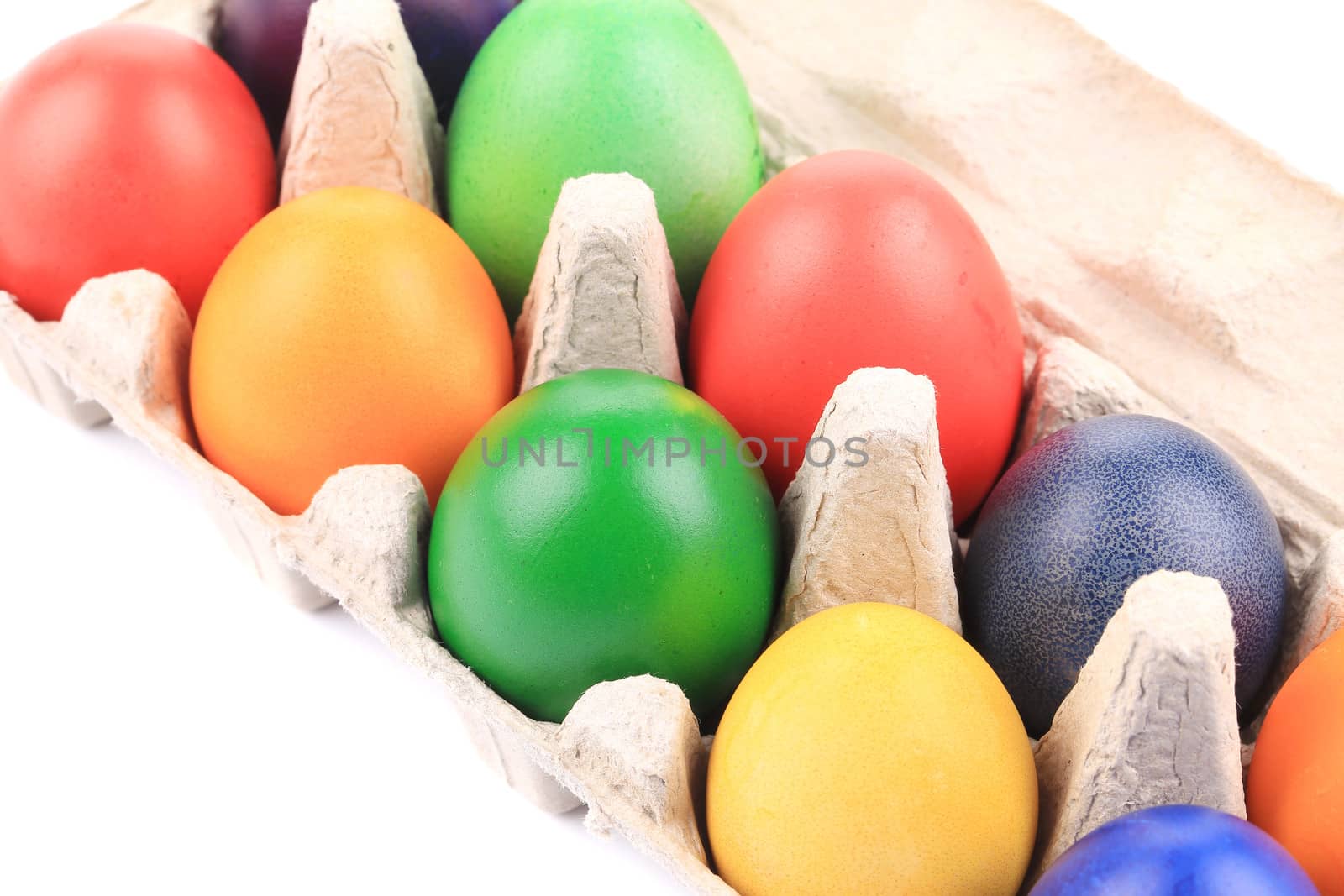 Cardboard egg box with Easter colored eggs. close up. isolated on a white background