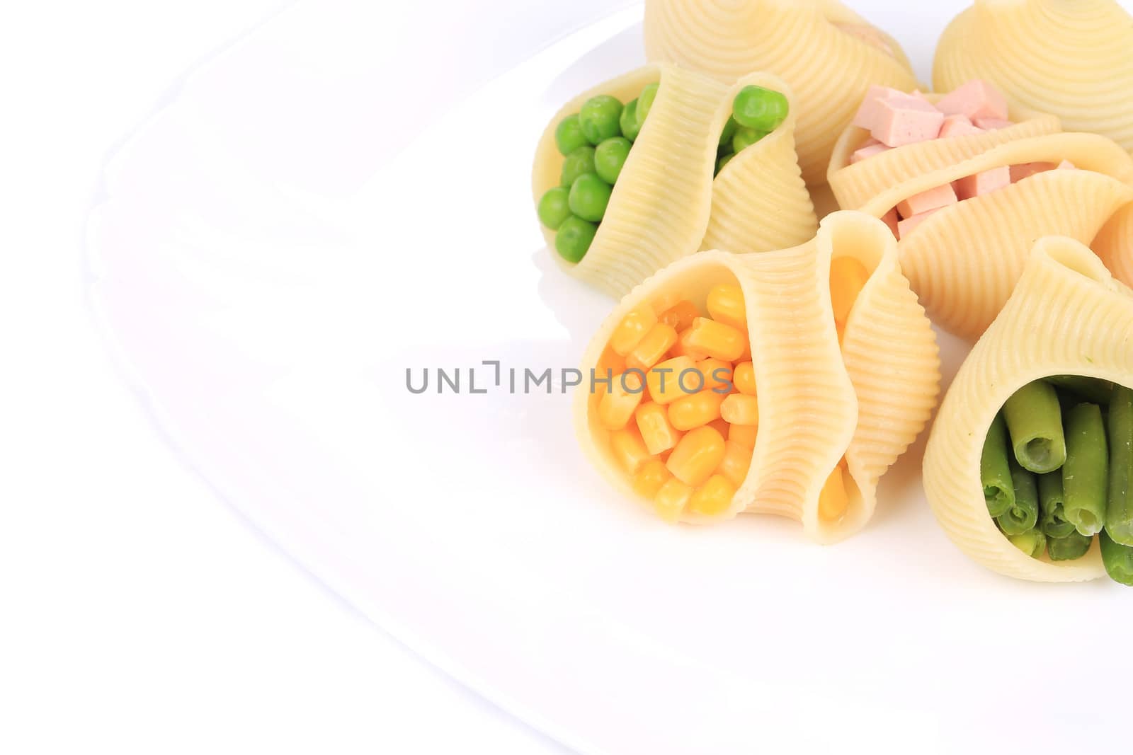 pasta shells stuffed with vegetables and sausage on a white plate.
