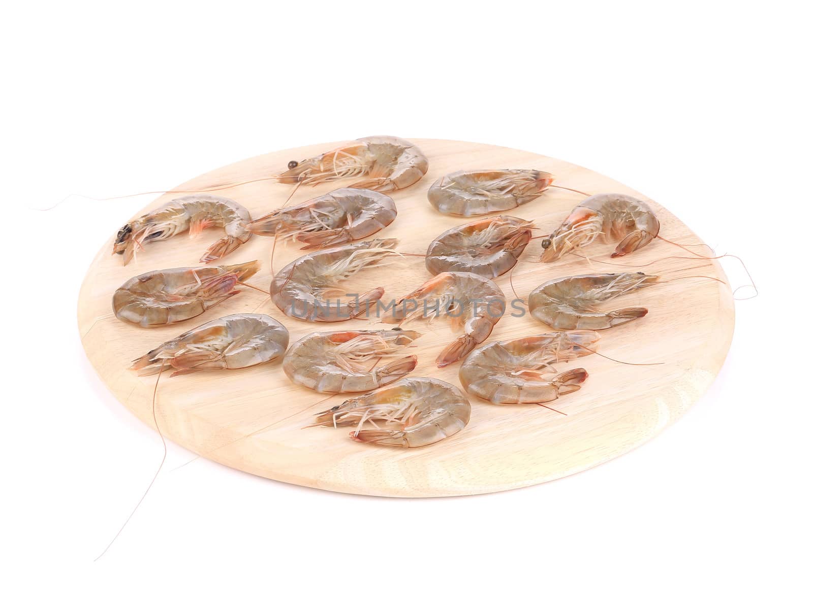 Raw shrimps on wooden round board. Isolated on a white background.