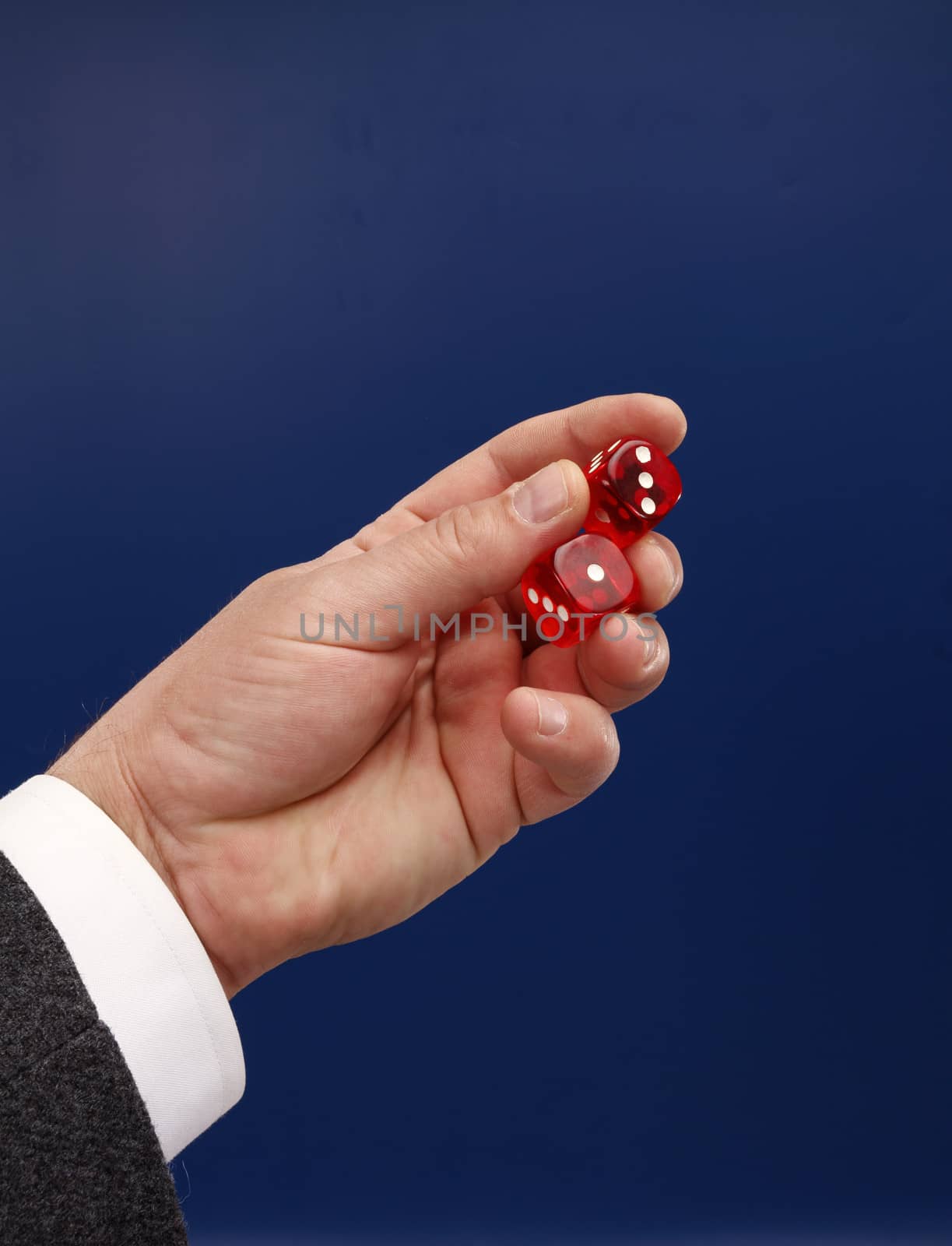 Two red dices in man's hand on blue