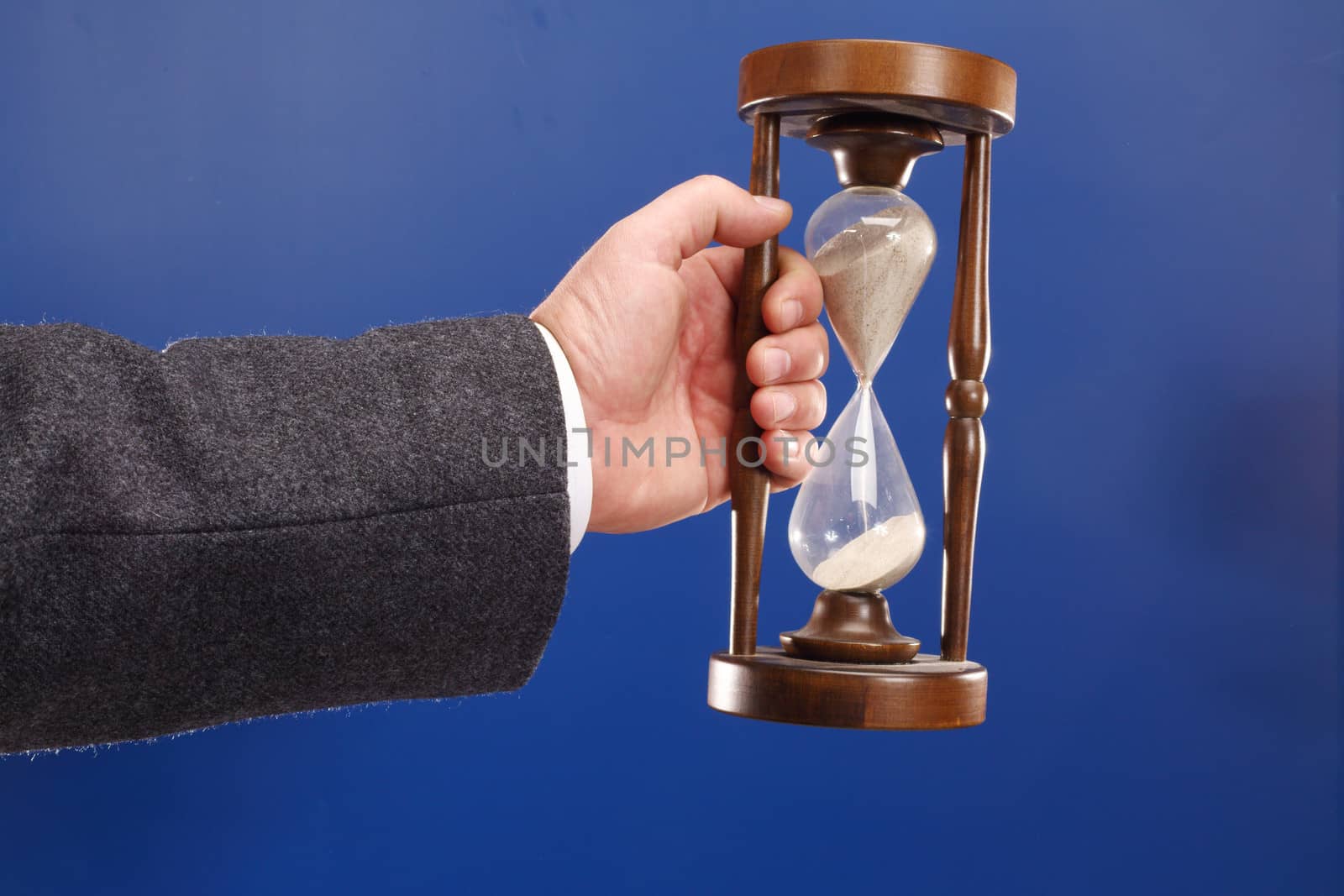 time for work concept - man holding sandglass over blue