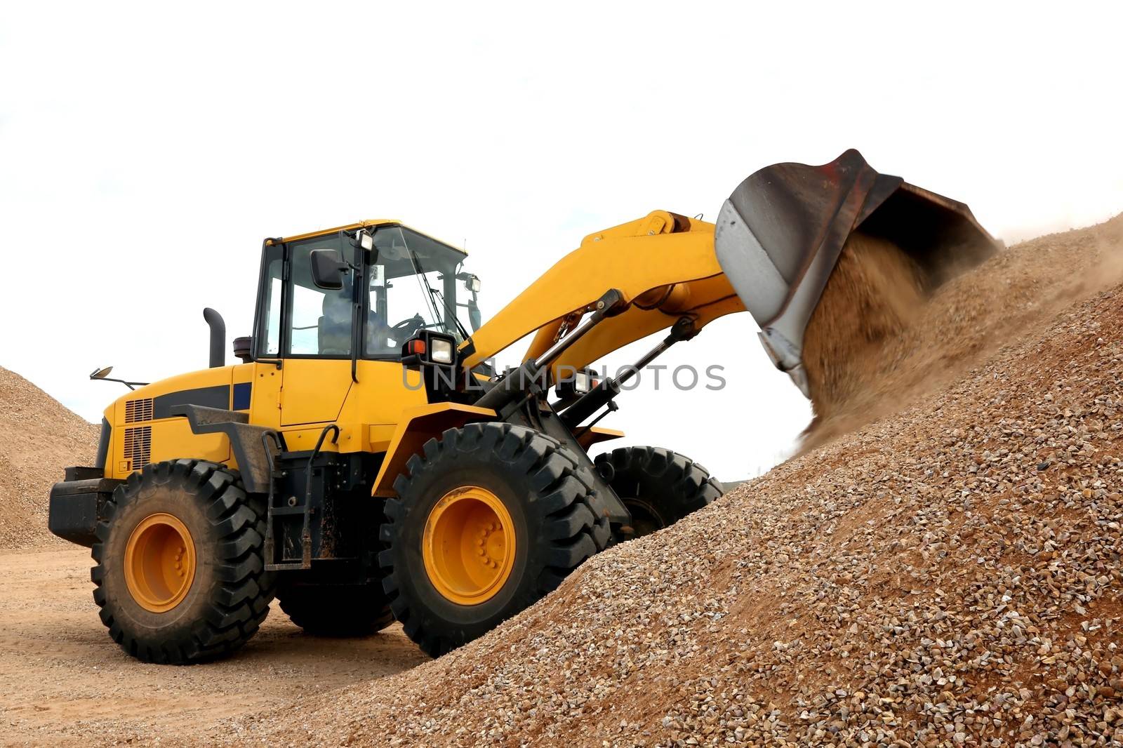 Bulldozer dumping stone and sand in a mining quarry