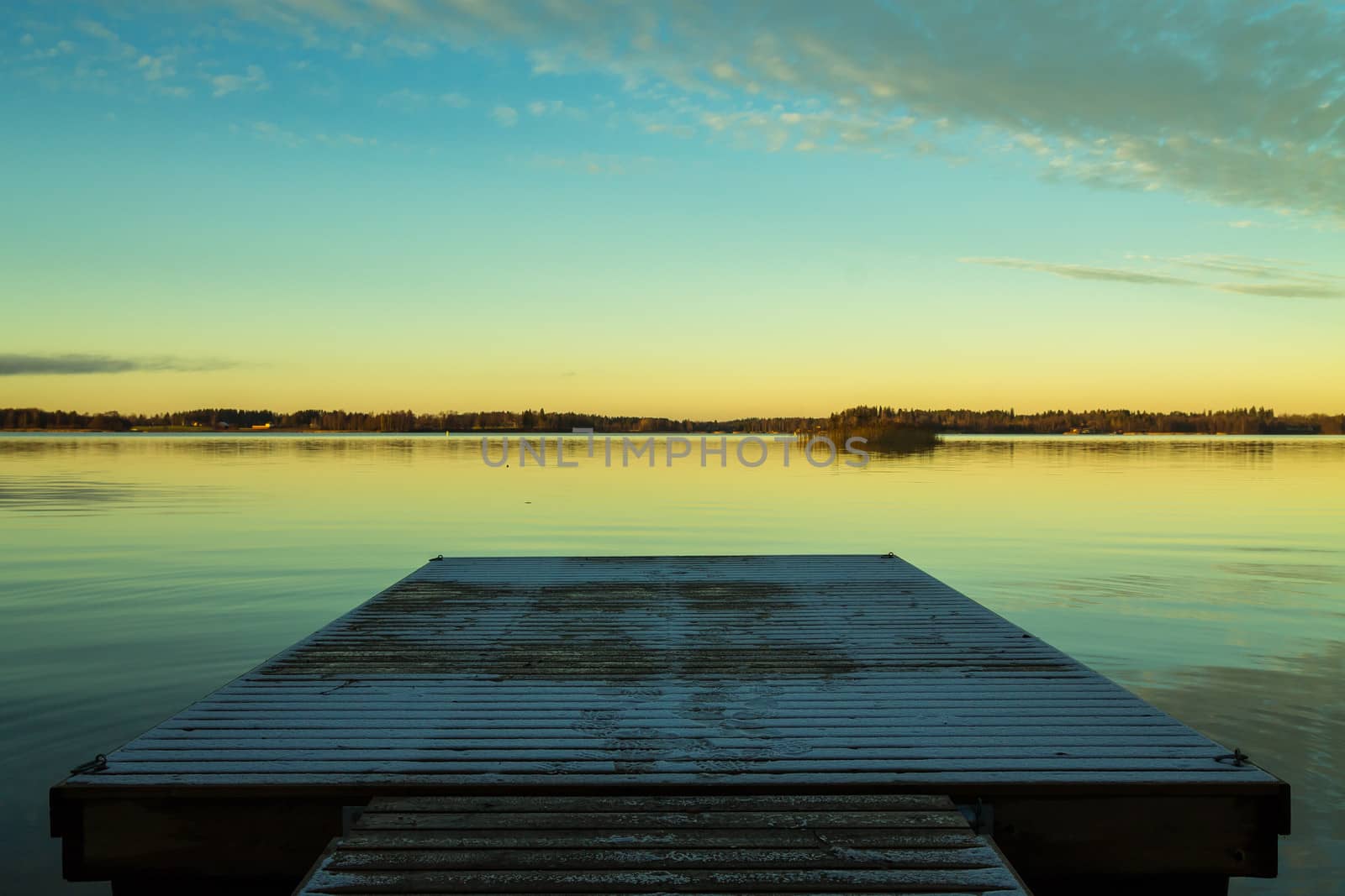 Scandinavian lake in the sunset with a frozen  jetty