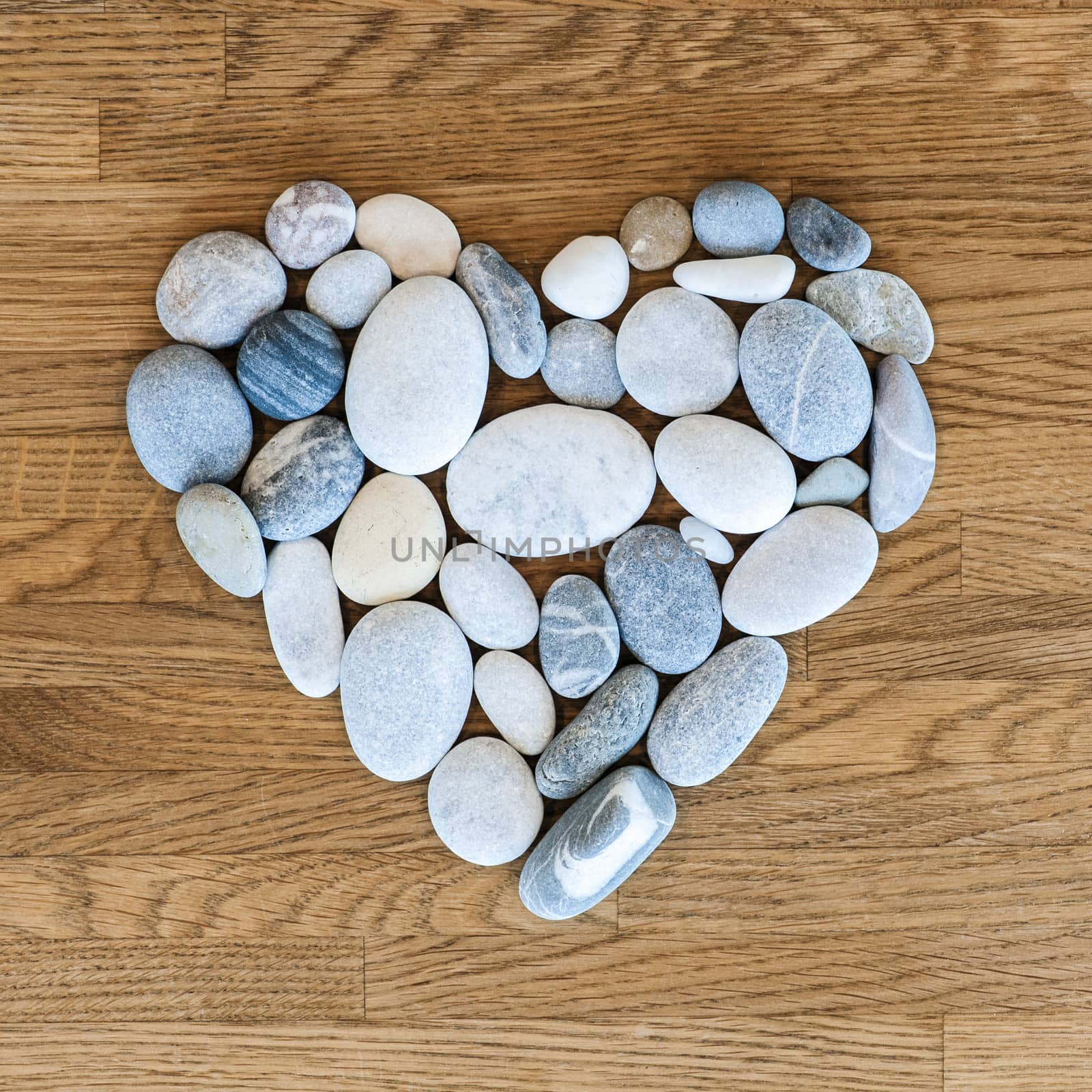 Stones arranged as a heart on a wooden background.