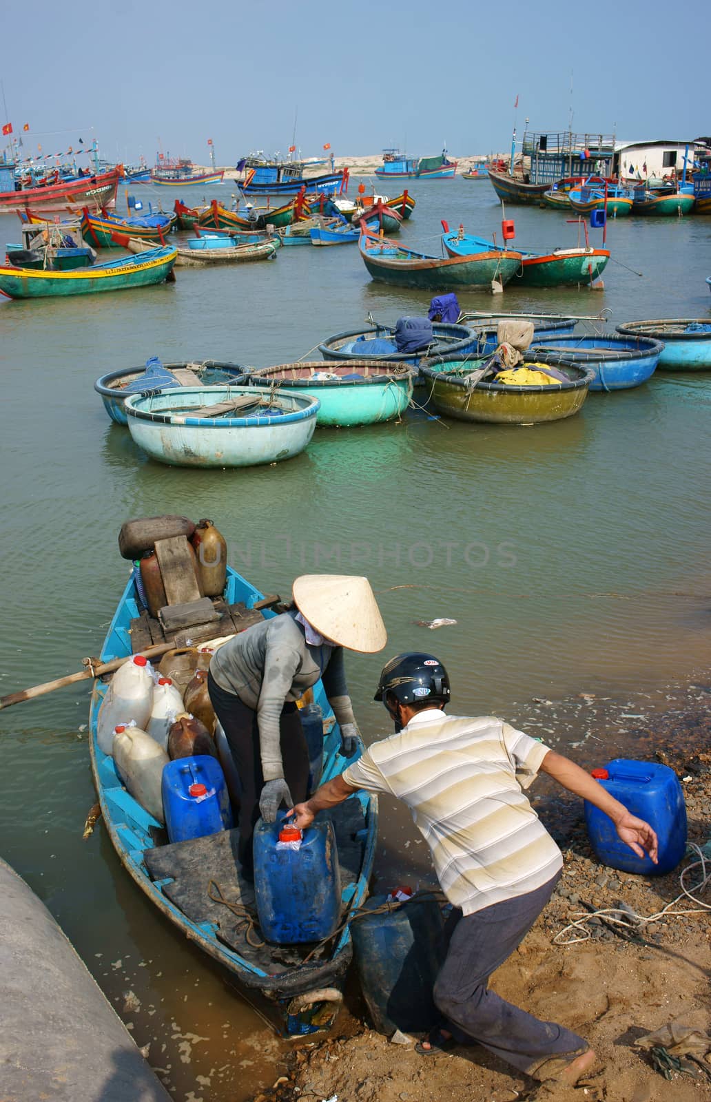 BINH THUAN, VIETNAM- JAN 20: Transportation people and goods by small wooden boat from fishing boat to shore, colorful fishing boat on habor on day at fishing village, Viet Nam, Jan 20, 2014