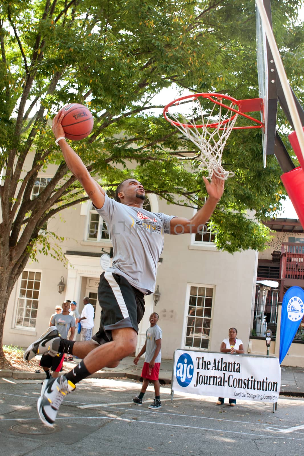 Athens, GA, USA - August 24, 2013:  A young man jumps to slam dunk the basketball in an impromptu dunk competition, in between games at a 3-on-3 basketball tournament held in the streets of downtown Athens.