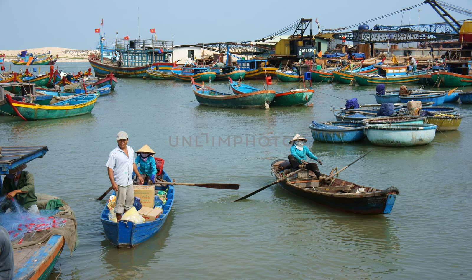 BINH THUAN, VIETNAM- JAN 20: Transportation people and goods by small wooden boat from fishing boat to shore, colorful fishing boat on habor on day at fishing village, Viet Nam, Jan 20, 2014