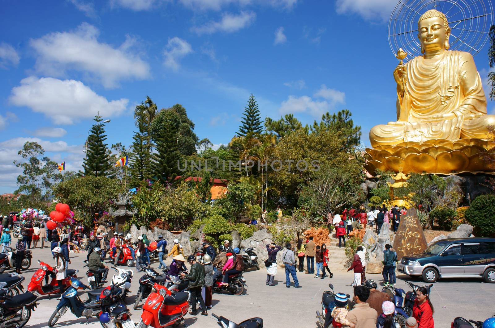 DA LAT, VIETNAM- JAN 31: People go to pagoda to pray lucky, yellow statue of buddha in blue sky, crowd of buddhist visit with belief, faith in buddhism, is traditional culture, viet Nam, Jan 31, 2014