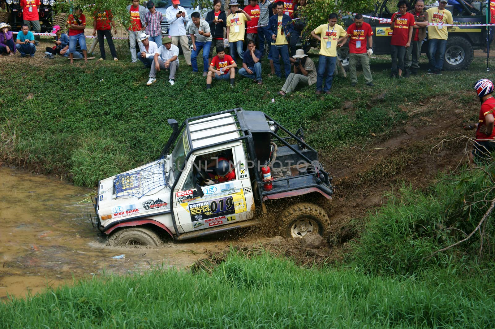 DAMBRI, VIET NAM- FEB 23: Racer offroad at terrain racing car competition, motor wade cross lake, splash mud, competitor  adventure in strong spirit, audience on lakeshore, VietNam, Feb 23, 2014