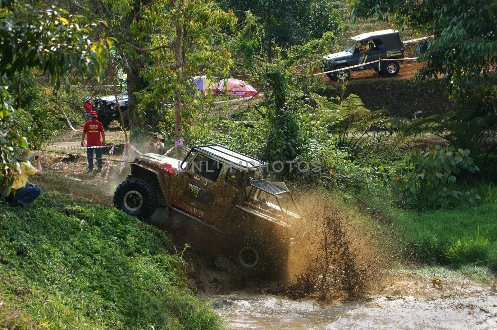 DAMBRI, VIET NAM- FEB 23: Racer offroad at terrain racing car competition, motor wade cross lake, splash mud, competitor  adventure in strong spirit, audience on lakeshore, VietNam, Feb 23, 2014