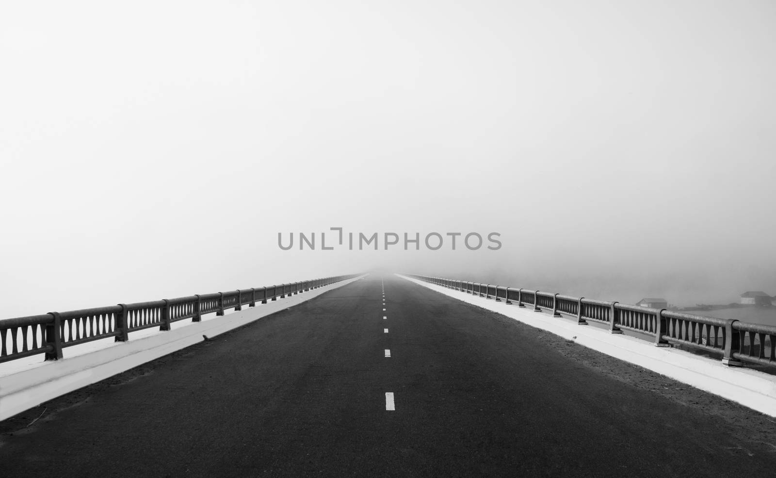 Asphalt road on big bridge cross the lake in fog at morning, the way like arrow, direction to white future, atmosphere full misty  