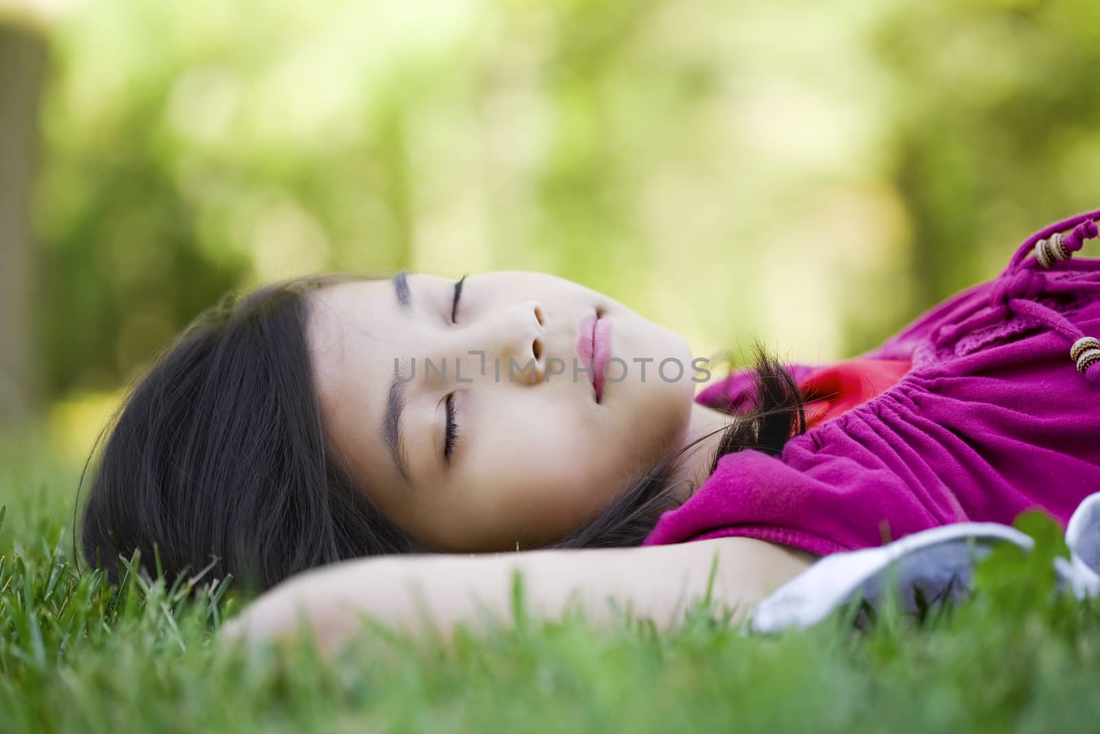 Little girl lying on grass lawn sleeping, close up view.